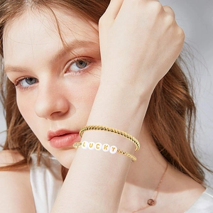 Golden beaded bracelet set with white letter beads spelling LUCKY on female model