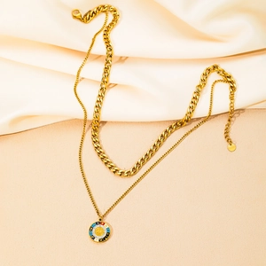 Dettaglio macro della collana a doppio strato dorata con tag S.Steel e ciondolo sole