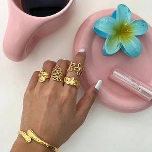 Detailed view of floral titanium steel rings and hammered gold bracelet on summer background