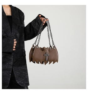 Brown bat-shaped jelly bag with cross pendant shown on model in black blazer