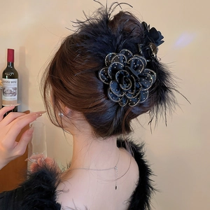 Detailed shot of an elegant black floral hair claw clip with feathers and rhinestones