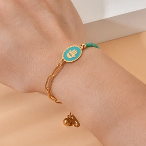 Gold Hamsa Hand paperclip chain bracelet with blue beads worn on a model's wrist