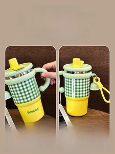 Detail of insulated coffee mug with green plaid texture and dual-mode carry handle