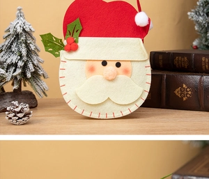 Detail of Santa Claus felt gift bag with red hat and sturdy handles on a festive wooden surface
