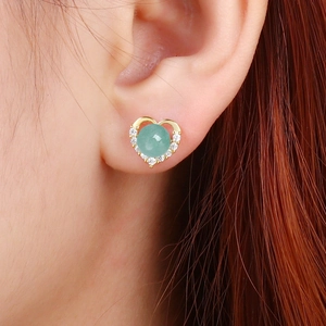 Elegant heart-shaped S925 silver stud earrings with green gemstone on model's ear