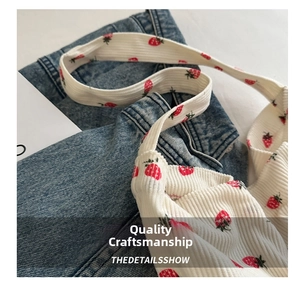 Detail of white corduroy tote bag with strawberry prints on blue denim background