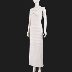 Détail d'une robe moulante blanche avec tissu texturé 3D et boucle dorée