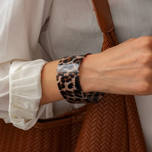 Close-up of wide leopard print acrylic cuff bracelet worn with elegant outfit