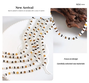 Close-up of beaded necklace with tiger eye stone and white chalcedony on a ceramic plate