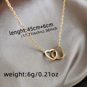 Macro shot showing dual interlocking hearts necklace dimensions on grey silk fabric