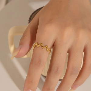 Close-up of 18k gold plated wave-shaped ring with textured surface on model's finger