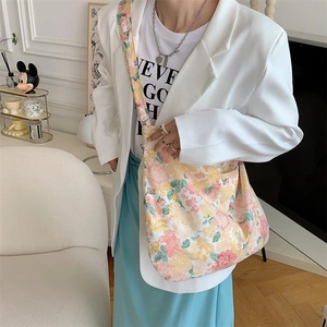 Detail view of floral print canvas tote bag paired with a white blazer and blue skirt