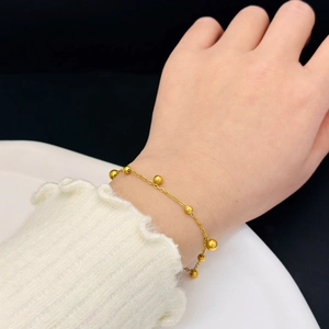 Minimalist gold ball bead bracelet in stainless steel worn on wrist with white tray