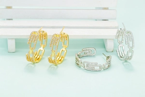 Close-up of gold and silver chain link earrings with pavé cubic zirconia on a mini bench