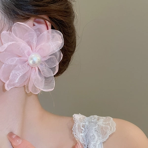 Close-up of pink chiffon flower earrings with white pearls worn by a model