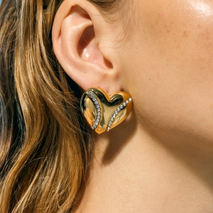 Detailed close-up of heart-shaped gold earrings with double rows of sparkling crystals