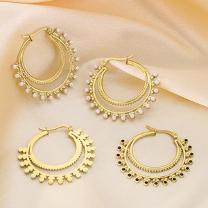 Bohemian gold layered hoop earrings set with pearls and black stones on champagne satin