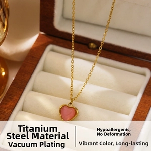 Detail of pink heart pendant on vacuum plated gold titanium steel chain in jewelry box