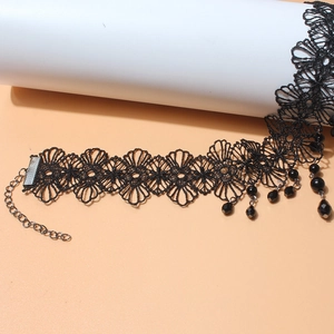 Dettaglio del choker in pizzo nero con motivi floreali e perline sfaccettate pendenti