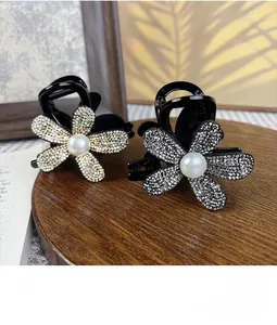 Detailed view of luxury flower hair claws with rhinestones and white pearls on wood