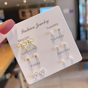 Detailed view of six pairs of elegant weekly stud earrings on a branded display card