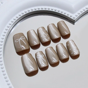 Champagne bow and polka dot press-on nails with a pearlescent cat-eye finish