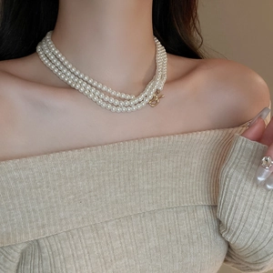 Detailed view of layered pearl necklace with gold OT toggle clasp on model neck