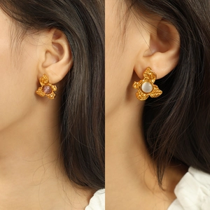 French vintage gold floral earrings featuring purple and grey cat-eye stones on a model