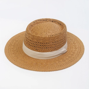 Close-up of woven straw texture and cream ribbon detail on flat top sun hat