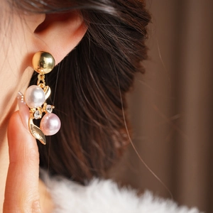 Gros plan sur des boucles d'oreilles feuille d'or vintage avec perles et zircon