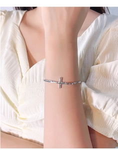 Close-up of a silver cross bracelet with textured finish worn on a woman wrist