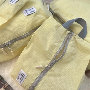 Detail of light yellow plaid travel organizer bag featuring gray zipper and durable handle