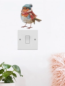 Détail d'un autocollant d'oiseau de Noël avec bonnet sur un interrupteur blanc
