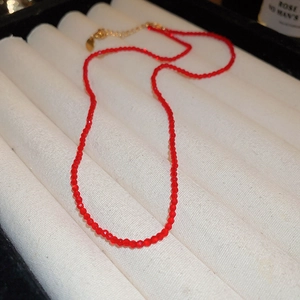 Detailed macro view of red crystal beaded necklace with gold clasp in white jewelry box
