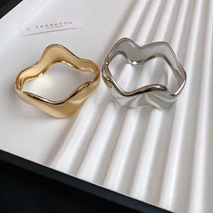 Irregular wavy open bangles in gold and silver finish with a polished minimalist design
