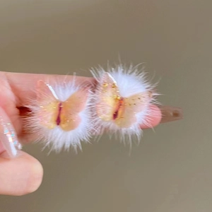 Detail of plush white hair clips featuring pink butterfly wings with gold leaf flakes