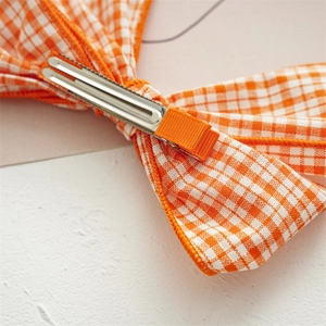 Back view of cute orange plaid fabric bow hair clip with durable metal duckbill clip