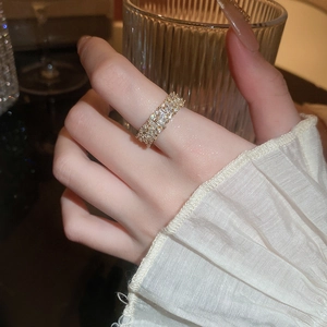 Detailed close-up of a gold hollow ring with pavé-set rectangular zircons on a finger