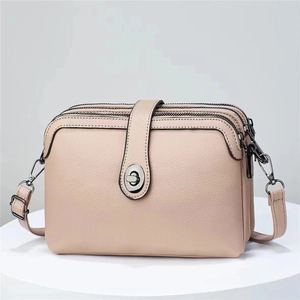 Detail of pink faux leather crossbody bag showing three zipper compartments and metal clasp