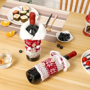 Detailed view of Christmas knit wine bottle covers with plush collars on a wooden table