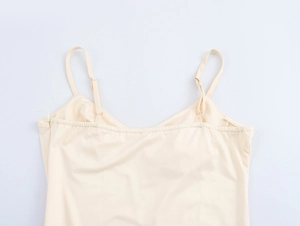 Detail view of adjustable spaghetti straps and V-neckline on a beige camisole dress