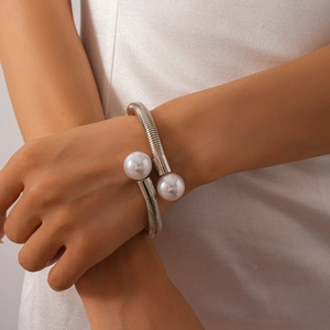 Close-up of minimalist silver spiral collar necklace featuring two large white pearls