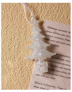 Close-up of a clear acrylic Christmas carriage ornament with white ribbon on a rustic background