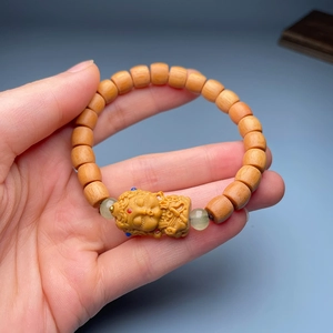 Detailed close-up of sandalwood bracelet with lotus carvings and green beads