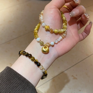Vue détaillée de bracelets en œil de tigre et perles avec breloque dorée au poignet