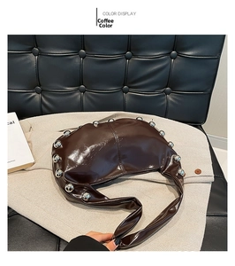 Detail view of coffee brown patent leather crescent bag with silver stud trim and wide strap