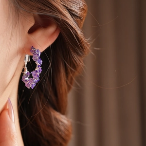 Close-up of elegant purple zircon hoop earrings with diamond-cut crystals on model