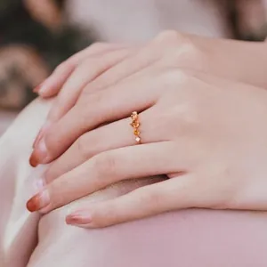 Detailed view of S925 silver ring with orange gemstones and gold finish on finger