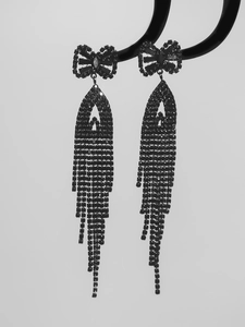 Close-up of black bow earrings with long tassel chains and shimmering cubic zirconia stones