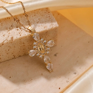 Golden cross necklace with Mary relief and white zircon stones on stone background